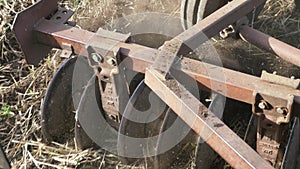 Closeup of plow attached to a tractor plowing a field.