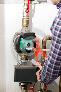 Closeup of plumber repairing heating system with red pliers