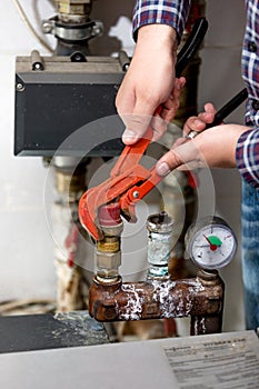 Closeup of plumber turning heating system valve with red pliers