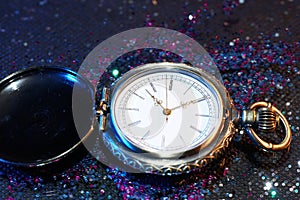 Closeup of a pocketwatch surrounded with colorful glitters