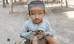 Closeup of a poor staring hungry orphan boy in a refugee camp with sad expression on his face and his face and clothes are dirty