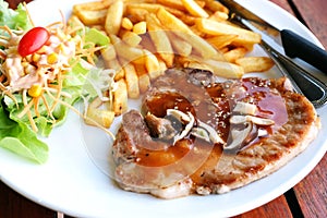 closeup pork chop steak with salad and frenchfried photo
