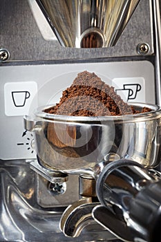 Closeup of a portafilter filled with fresh ground coffee under g
