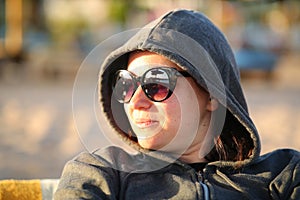 Closeup portrait of a 35 year old caucasian lady wearing sunglasses and hoodie. Natural look with wrinkles, birthmarks and no make