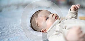 Closeup portrait of adorable baby boy lying on his back and relaxing in the bed. Copy space