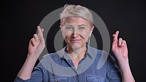 Closeup portrait of adult attractive caucasian female having her fingers crossed and praying in hope being worried while