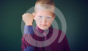 Closeup portrait of angry Caucasian boy showing fist, demanding justice, his rights. Boy isolated green wall background.