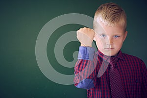 Closeup portrait of angry Caucasian boy showing fist, demanding justice, his rights. Boy isolated green wall background.