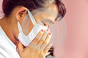 Closeup portrait of Asian lady wearing a face mask and putting a hand on her mouth because cough and illness. Health care concept