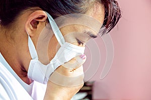 Closeup portrait Asian lady wearing a face mask and putting a hand on her mouth because of cough and illness. Health care concept