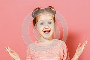 Closeup portrait of attractive charming cheerful little girl with buns over pink background.