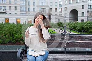 Closeup portrait of attractive female with eyeglasses in hand. Poor young girl has issues with vision. She rubs her nose and eyes