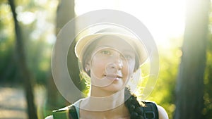 Closeup portrait of attractive tourist girl smiling and looking into camera while hiking beautiful forest