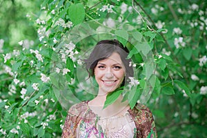 Woman in spring garden. Beautiful girl in spring landscape background. Springtime. Female face with healthy skin and healthy teeth