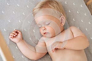 Closeup portrait of baby boy napping in his bed after active play in his bedroom