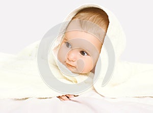 Closeup portrait of baby under towel on the bed