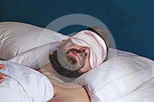 Caucasian bearded man in eyemask sleeping in bed photo