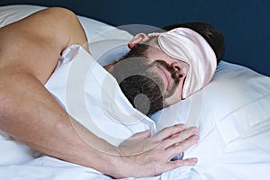 Caucasian bearded man in eyemask sleeping in bed photo