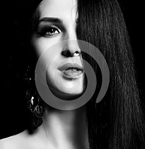 Closeup portrait of beautiful brunette girl with healthy long hair and earrings black and white