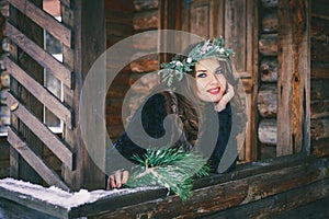 Closeup portrait of beautiful brunette girl in a wreath on a wooden background traditional Ukrainian or Russian house.