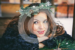 Closeup portrait of beautiful brunette girl in a wreath on a wooden background traditional Ukrainian or Russian house.