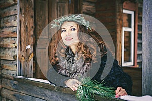 Closeup portrait of beautiful brunette girl in a wreath on a wooden background traditional Ukrainian or Russian house.