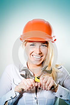 closeup portrait of beautiful charming young woman happy smiling in a helmet with two wrench