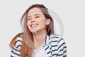 Closeup portrait of beautiful happy young woman with long hair smiling cheerfully. Charming female smile broadly showing her white