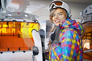 Closeup portrait of beautiful skier girl wearing mask and holding ski, enjoying winter holidays