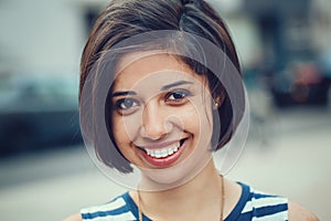 Closeup portrait of beautiful smiling young latin hispanic girl woman with short dark black hair bob