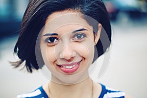 Closeup portrait of beautiful smiling young latin hispanic girl woman with short dark black hair bob