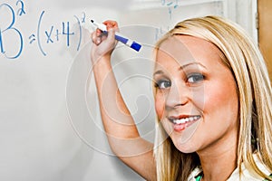 Closeup portrait of beautiful student solving algebra equation on whiteboard in classroom