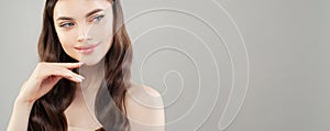 Closeup portrait of beautiful woman with clear skin smiling and looking aside on gray banner background