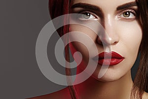 Closeup portrait with of beautiful woman face. Red color of fashion lip makeup, clean shiny skin and strong eyebrows