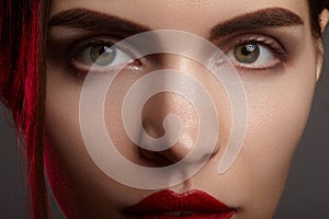 Closeup portrait with of beautiful woman face. Red color of fashion lip makeup, clean shiny skin and strong eyebrows