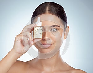 Closeup portrait beautiful woman holding face serum over eye while posing with copyspace. Young caucasian model isolated