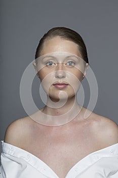 Closeup portrait of a beautiful woman with natural makeup and tight hair, wear white shirt, isolated grey background.