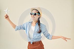 Closeup portrait of beautiful woman in straw hat holding airplane model in hand, dreaming about holidays