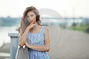 Closeup portrait of beautiful woman in summer dress posing in city river park pier enjoying weekend. Playful and beautiful