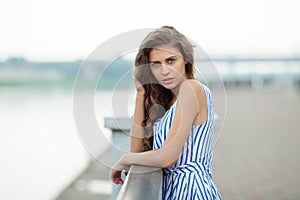 Closeup portrait of beautiful woman in summer dress posing in city river park pier enjoying weekend. Playful and beautiful