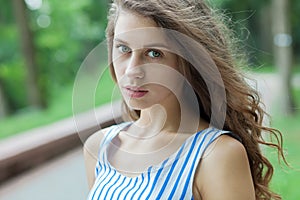 Closeup portrait of beautiful woman in summer dress posing in green park enjoying weekend. Playful and beautiful caucasian girl on