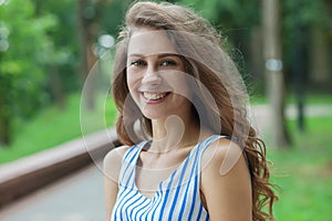 Closeup portrait of beautiful woman in summer dress posing in green park enjoying weekend. Playful and beautiful caucasian girl on