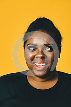 closeup portrait of a beautiful young african american woman with afro hairstyle on yellow background