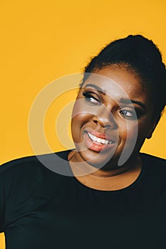 closeup portrait of a beautiful young african american woman smiling with afro hairstyle on yellow background