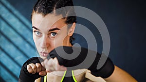 Closeup portrait beautiful young boxing woman training punching in gym