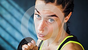 Closeup portrait beautiful young boxing woman training punching in gym