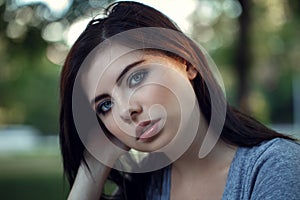 Closeup portrait of beautiful young Caucasian woman with black hair, blue eyes, looking in camera