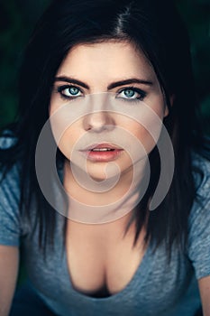 Closeup portrait of beautiful young Caucasian woman with black hair, blue eyes, looking in camera