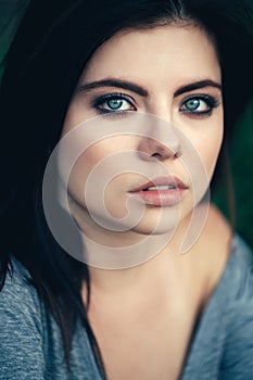 Closeup portrait of beautiful young Caucasian woman with black hair, blue eyes, looking in camera