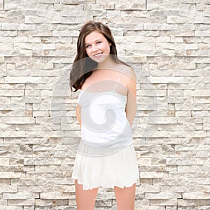 Closeup portrait of a beautiful young smiling woman in front of white marble background